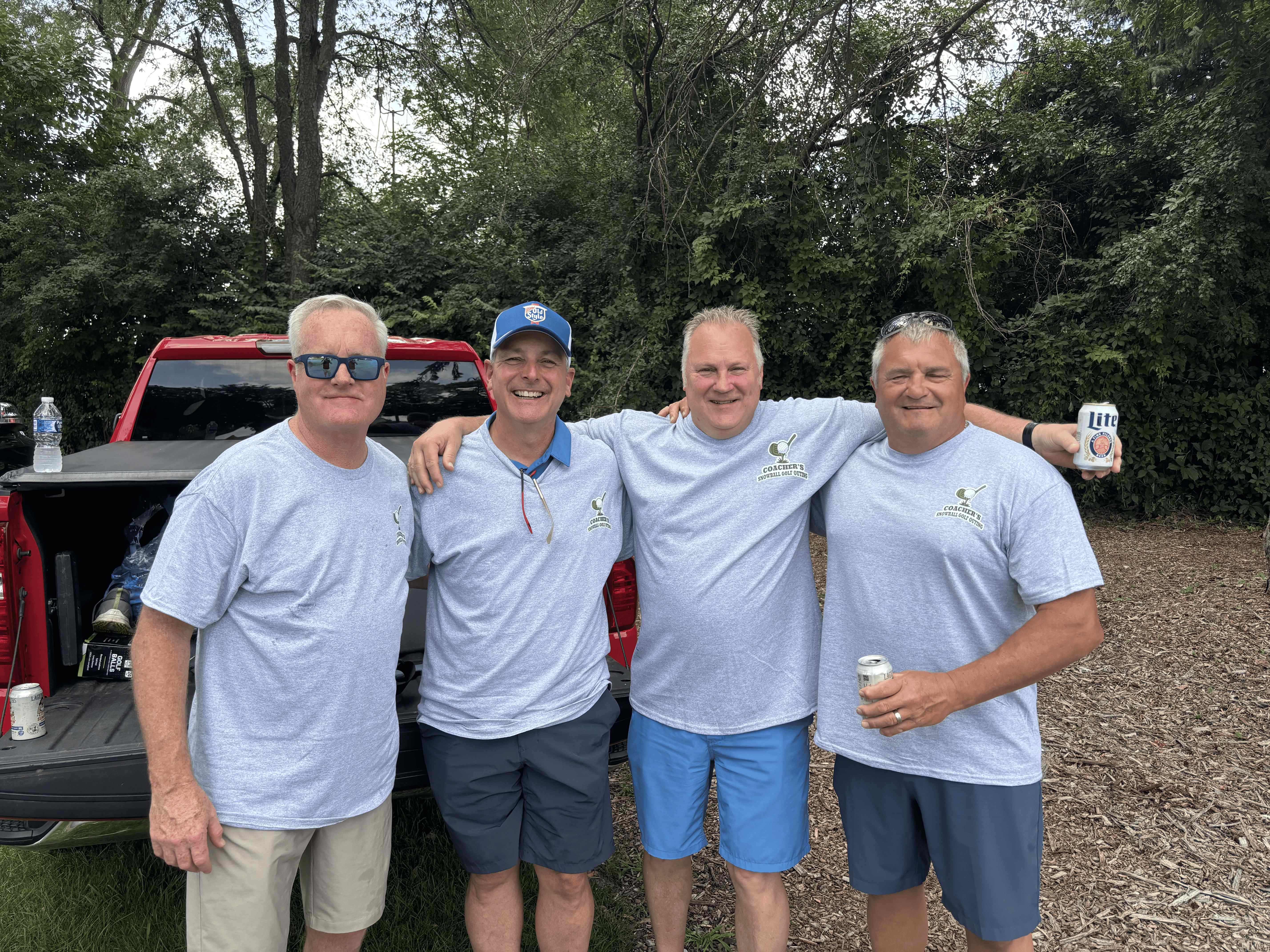 Four men in matching Coacher's Snowball Golf Outing shirts smiling together at the inaugural outing