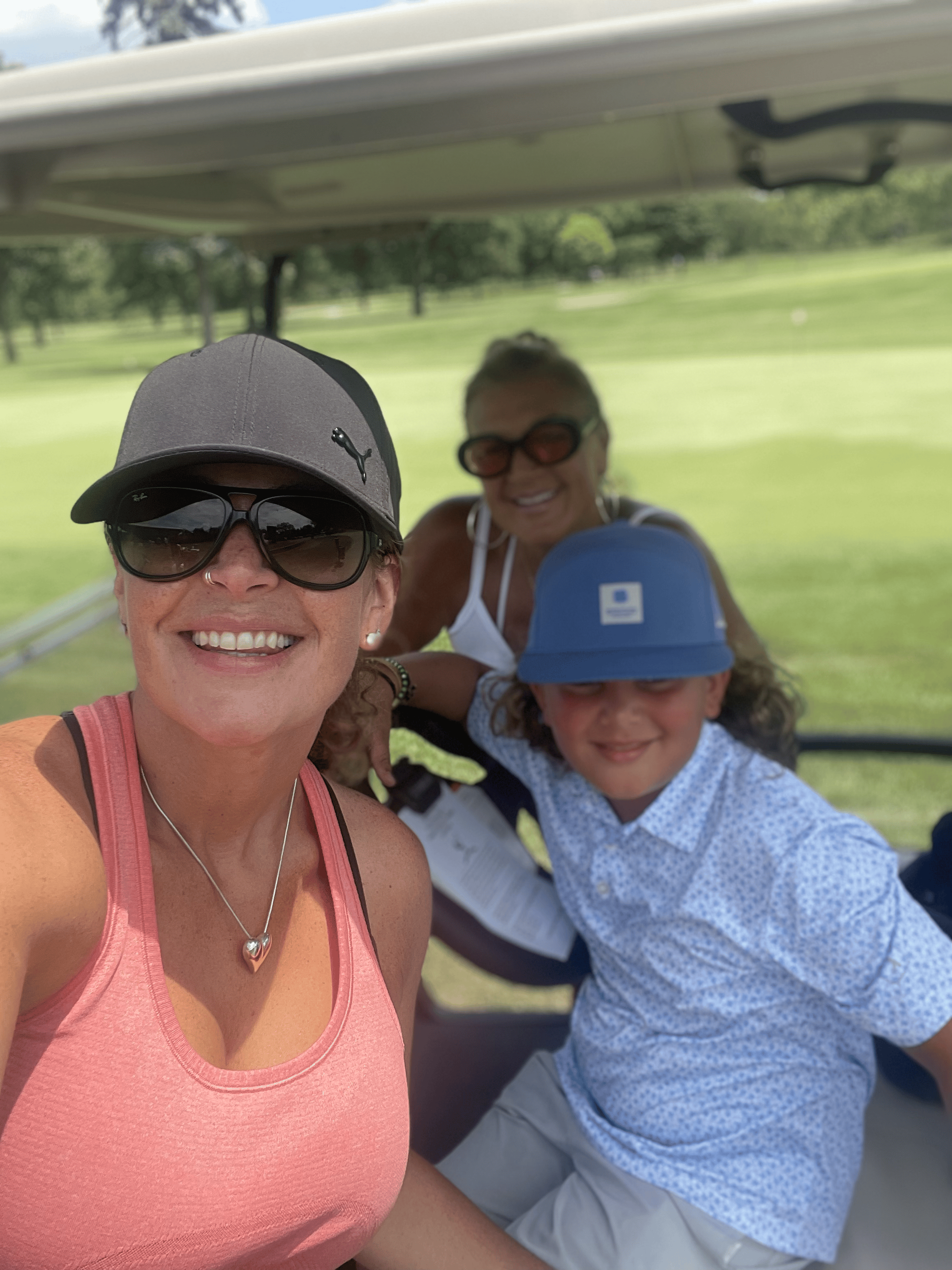 A family selfie in the golf cart, smiling together during the inaugural outing